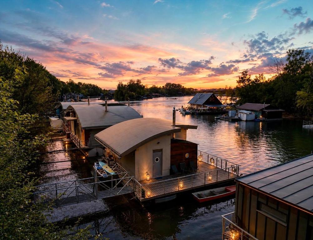 a group of houses on a river at sunset at Sunset view Housboat with sundeck,AC&Heating in Bratislava