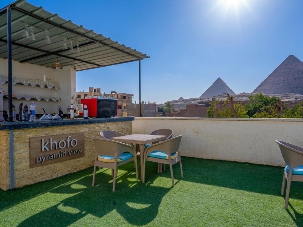 a table and chairs on a roof with pyramids in the background at khofo pyramids view in Cairo