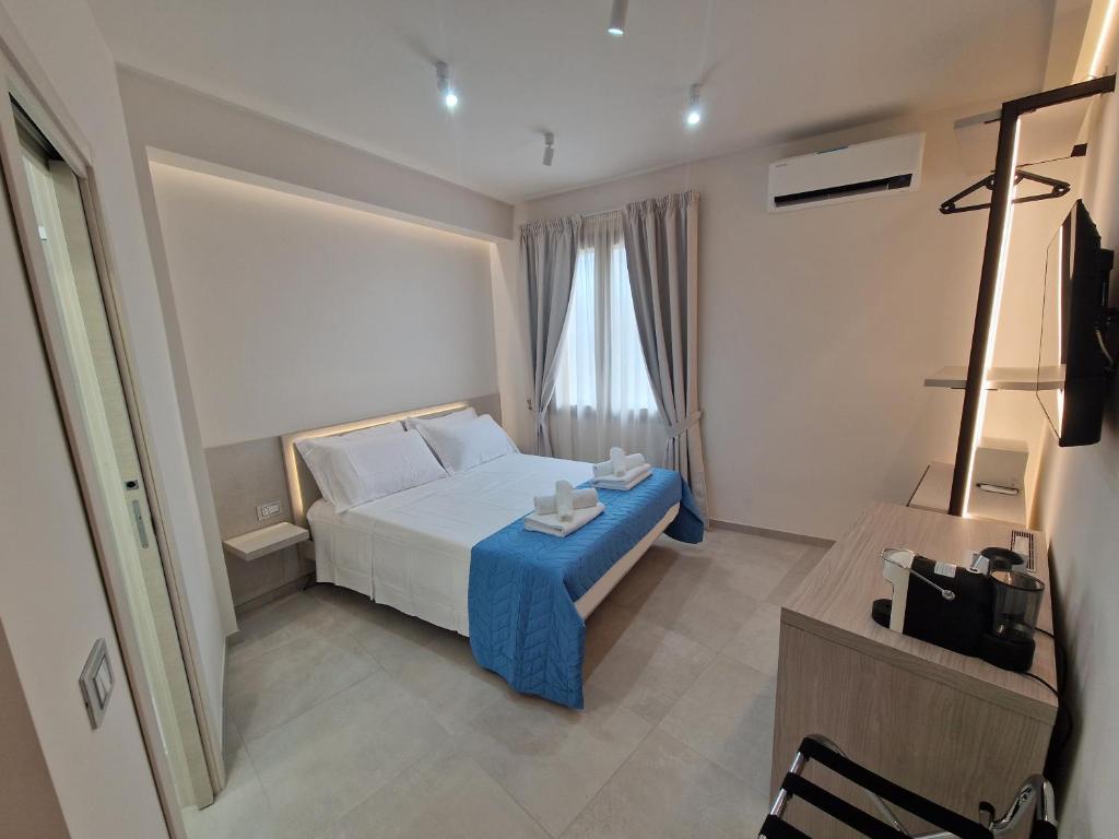 a bedroom with a white bed and a blue table at Acqua Marina Rooms in La Caletta