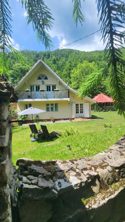 a house with two chairs and an umbrella at Casa de vacanta Julius in Padis