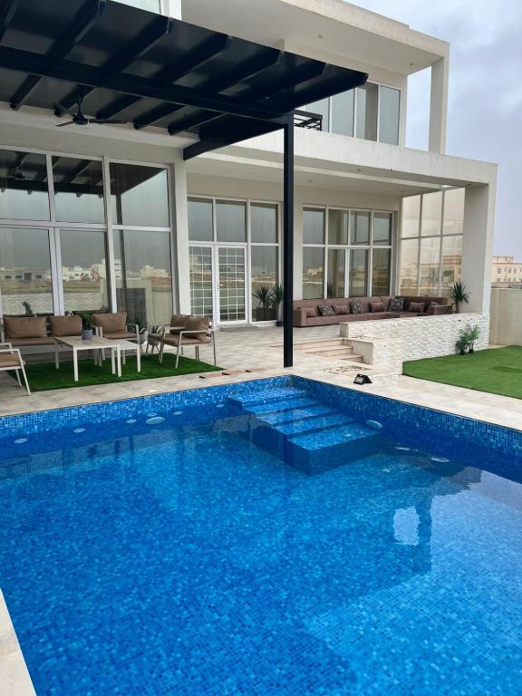 a swimming pool in front of a house at فيلا صلاله بالم salalah palm villa in Salalah