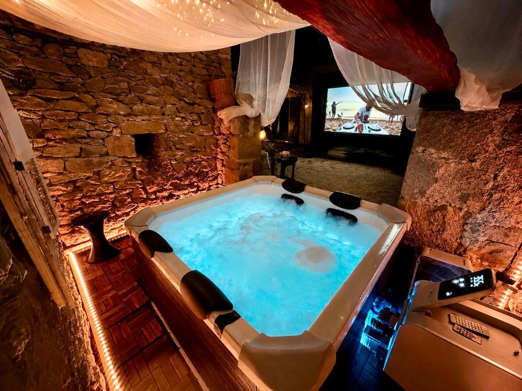 a large bath tub in a room with a stone wall at Domaine VALENQUERCY in Cazillac
