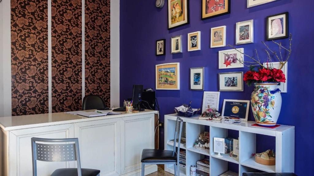 a room with a purple wall with a desk and chairs at Albergo Miramonti in Gangi