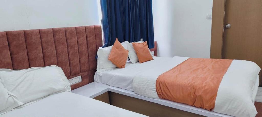 a hotel room with two beds with orange pillows at Hotel Radhe Inn in Gandhinagar