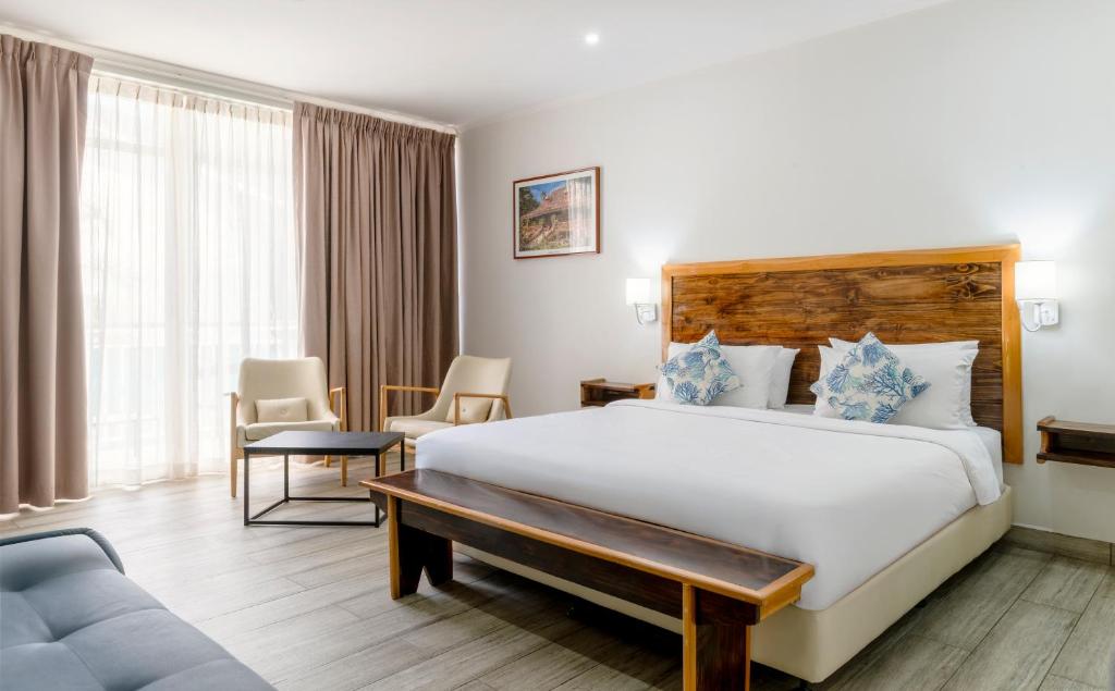 a hotel room with a large bed and a couch at Voilà Beau Vallon in Beau Vallon