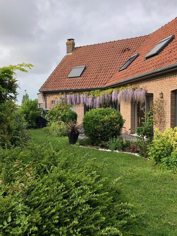 a house with purple wisterias on the roof at Au Jardin de Mireille in Leffrinkhoucke