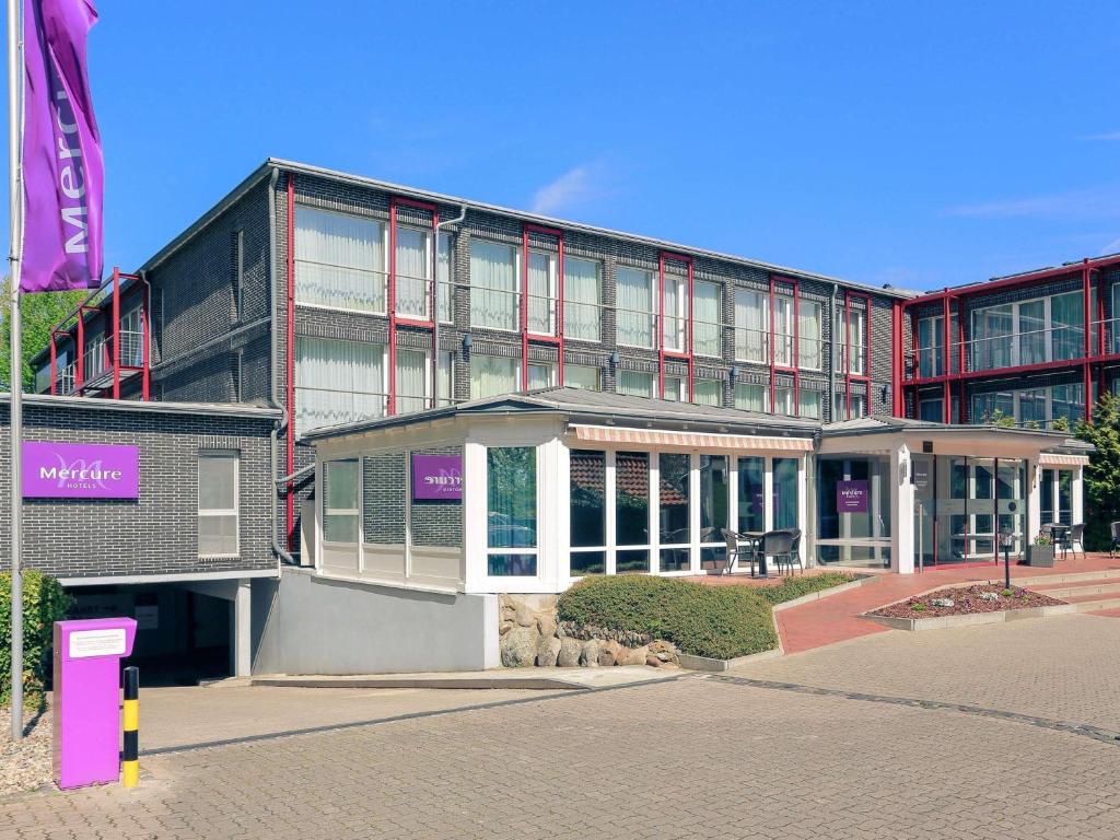 a large building in front of a building at Mercure Hotel am Entenfang Hannover in Hannover