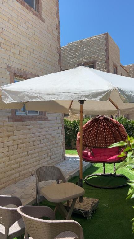 a table and chairs under a white umbrella at Chalet in La mera north coast in Zāwiyat al ‘Awwāmah