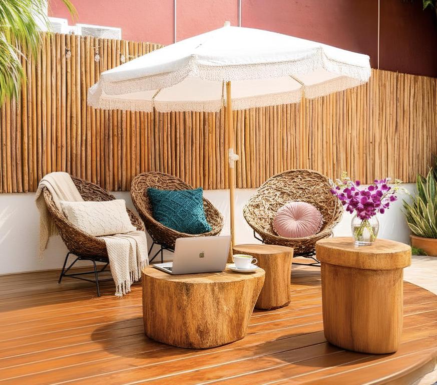 a table with an umbrella and chairs and a laptop at Centro Mornings, King & 2BR Suites, Sleeps 2-8, Kitchen WiFi AC, Beach, 5th Ave, ADO & Ferry 4 Min in Playa del Carmen