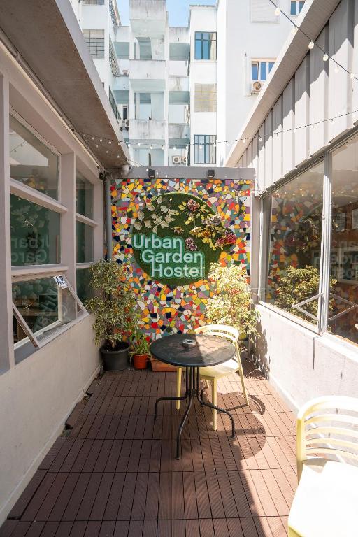 a patio with a table and a sign on a building at Urban Garden Hostel in Lisbon