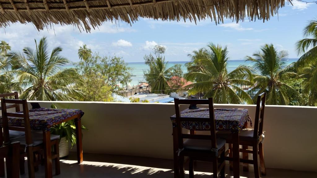 a balcony with two tables and a view of the ocean at Rafiki Hotel Nungwi Beach in Nungwi