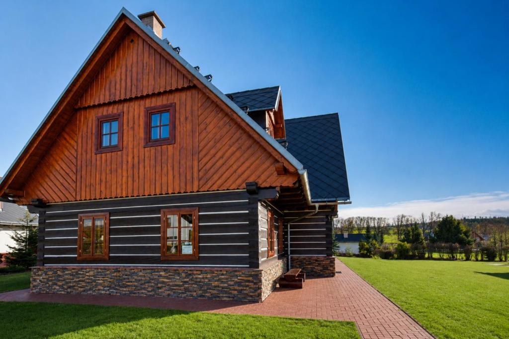 a house with a wooden roof and a green lawn at Wellness Chalupa Theo in Vrchlabí