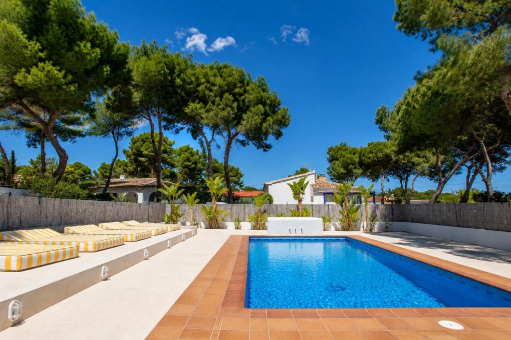 a swimming pool in a backyard with a fence and trees at Quinta la Sal by SingularStays in Jávea