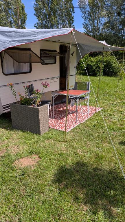 a tent with a picnic table in a field at Caravane Cosy - 5min Circuit 24h du Mans in Changé