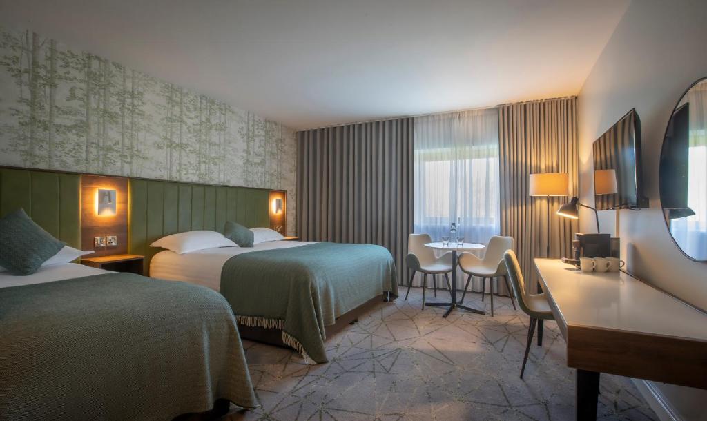 a hotel room with two beds and a table and chairs at Hoban Hotel Kilkenny in Kilkenny