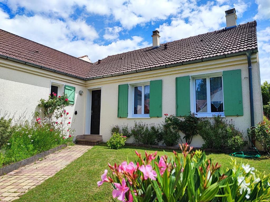 a house with green shutters and a yard with flowers at Maison Familiale - 7 personnes - Parking privé & Jardin - Disney 24 min in Tournan-en-Brie