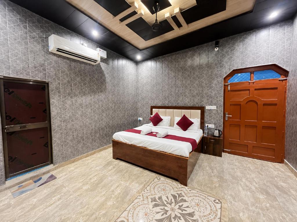a bedroom with a bed and a wooden door at Hotel Shreeji Palace - OPP Hanuman Garhi Mandir in Ayodhya