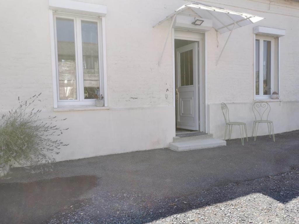 a white house with two chairs and a door at La douce Campagne in Flavigny-le-Grand-et-Beaurain