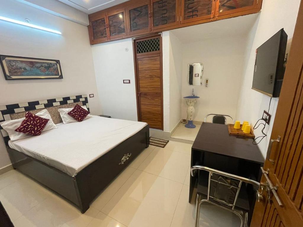 a bedroom with a bed and a desk and a television at Govind Atithi grah in Ayodhya