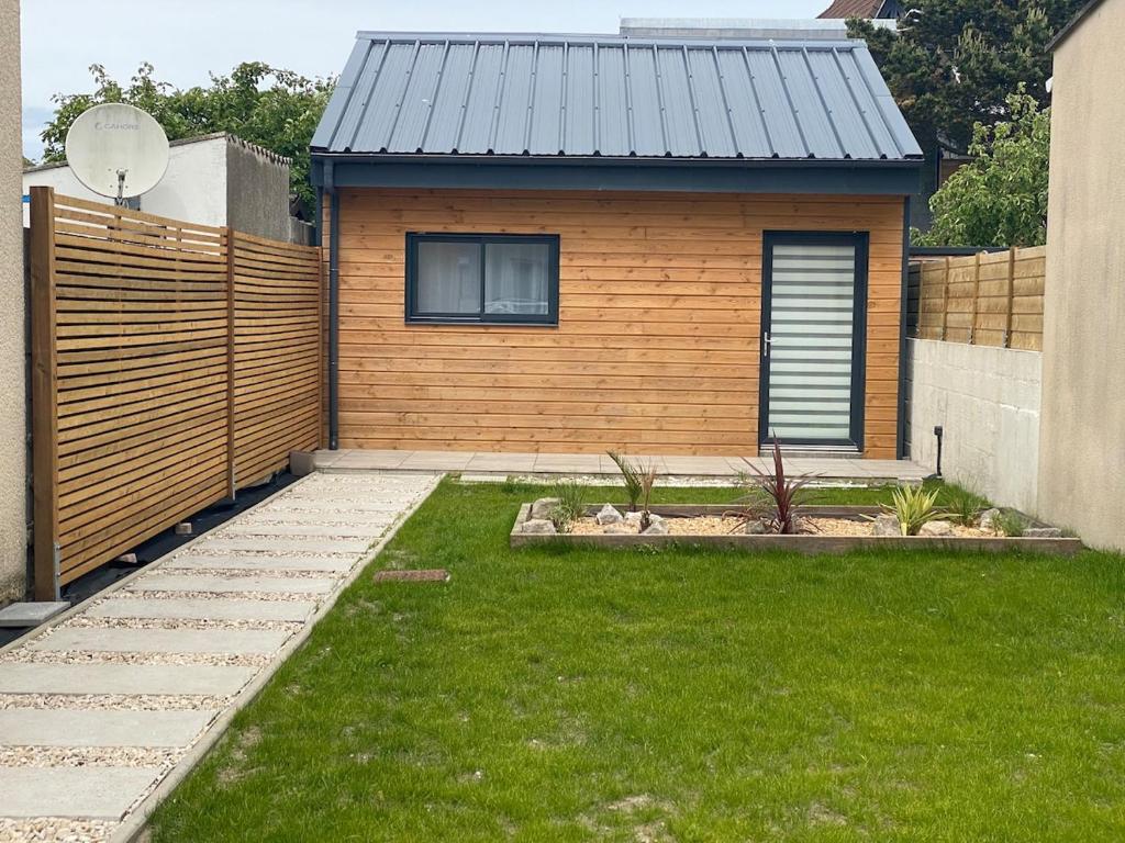 a house with a fence and a green yard at La Cabane Marine in Sangatte