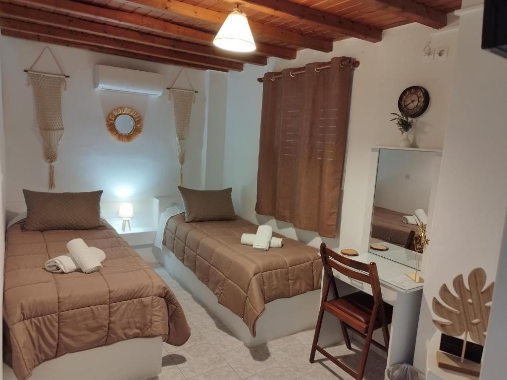 a bedroom with two beds and a desk and a chair at MMrooms Μονά κρεβάτια 2ος όροφος in Tinos