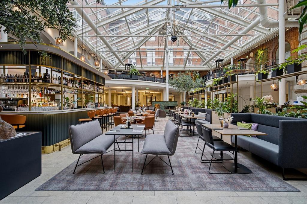 a restaurant with tables and chairs and a glass ceiling at Hotel Alte Post Flensburg in Flensburg