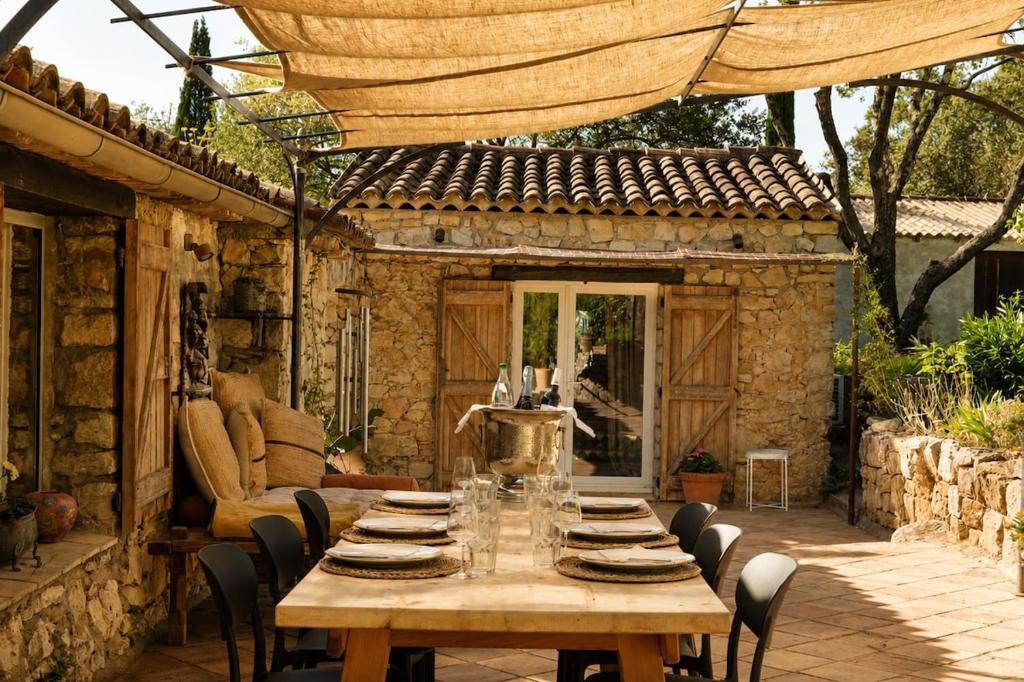 a wooden table and chairs in a patio at Le Mas des Chènes in Taradeau
