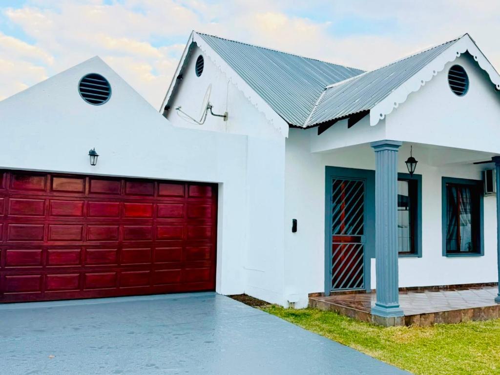 a white house with red garage doors at The Private Place in eMalahleni