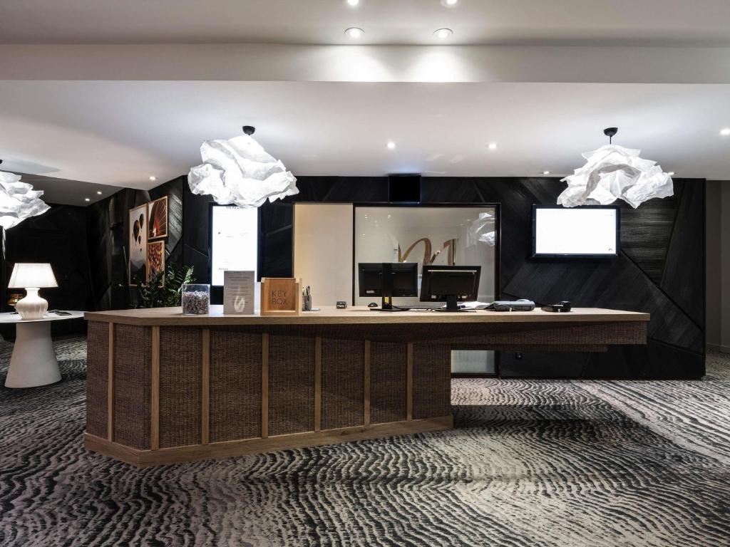 a reception desk in a room with a mirror at Mercure Grenoble Meylan in Meylan