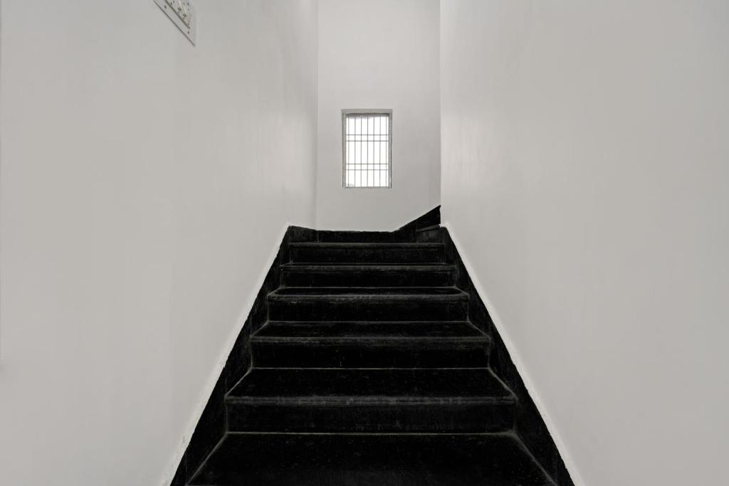 a staircase leading up to a white room with a window at Hotel O Radha Krishna Family Hotel in Naubatpur
