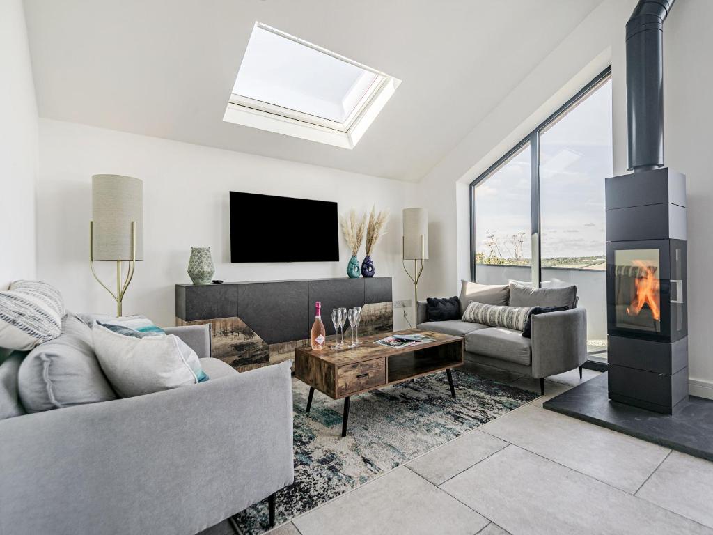 a living room with a fireplace and a tv at The Old Coach Garage in Gerrans
