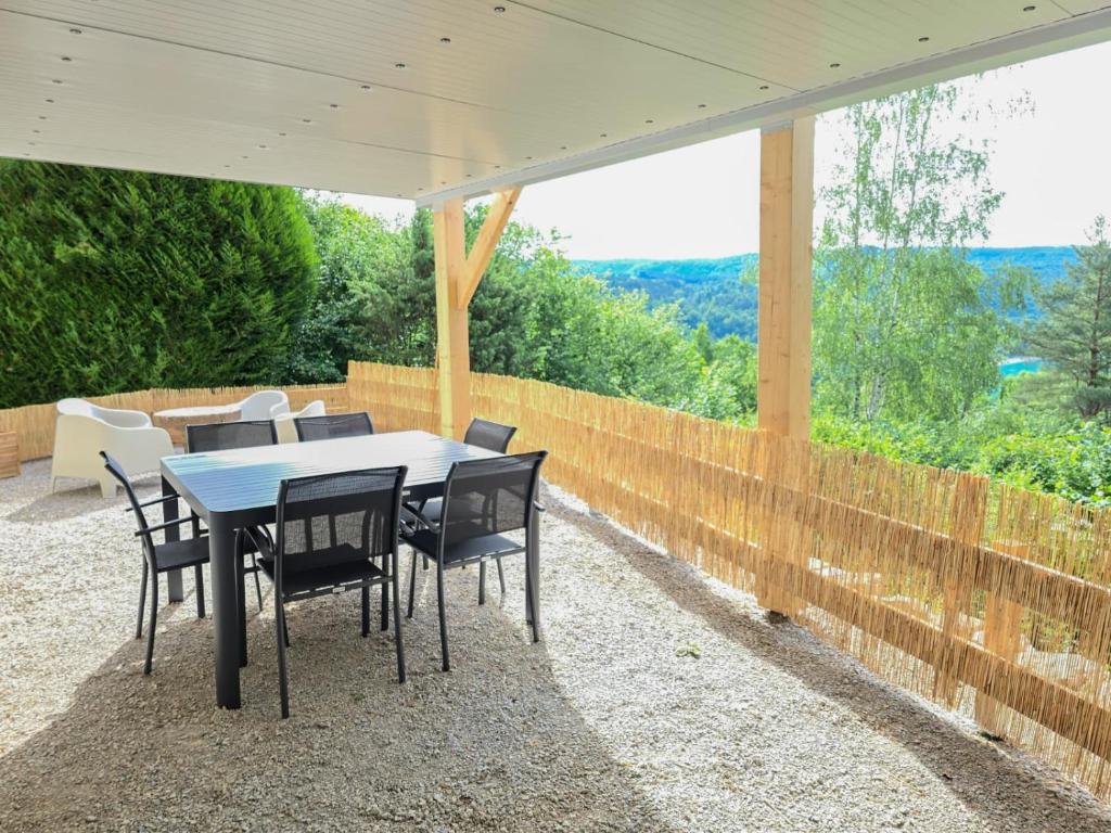 a table and chairs under an umbrella on a patio at Les Reflets Verts - Lac de Vouglans in Maisod