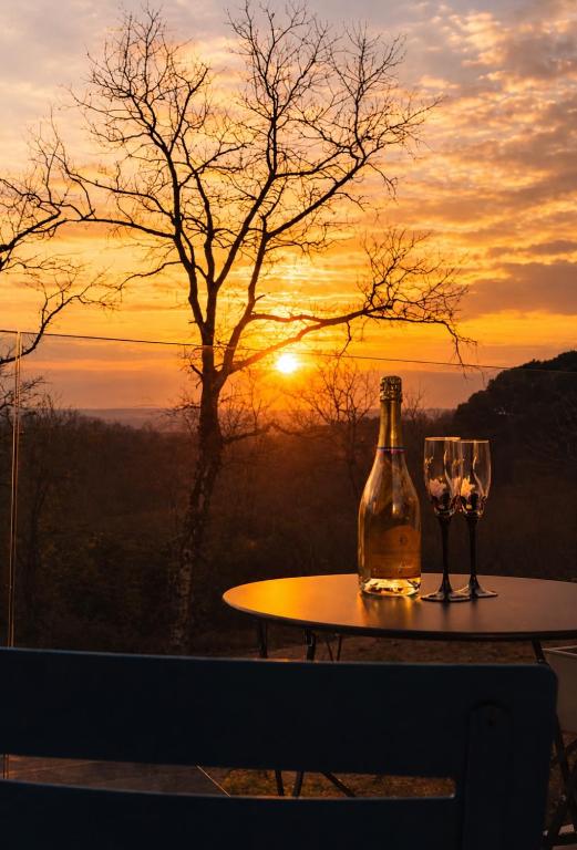 a bottle of wine and two glasses on a table with the sunset at STUNNING VIEW, chambre en forêt proche BORDEAUX in Bouliac