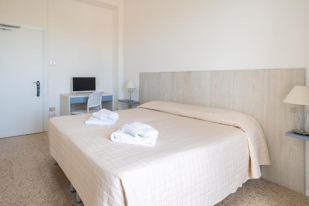 a bedroom with a white bed with towels on it at Hotiday Castelsardo Spiaggia in Castelsardo
