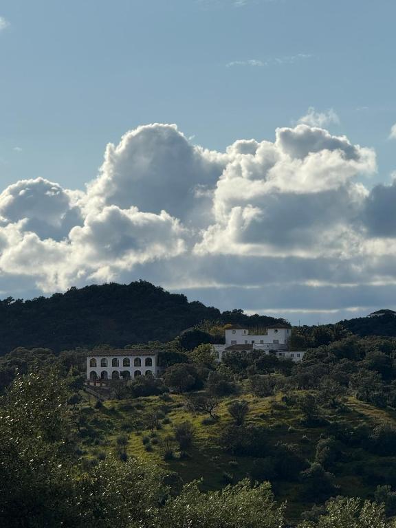 a group of white buildings on a hill with clouds at Finca Jaralta de Carmen in La Puebla de los Infantes