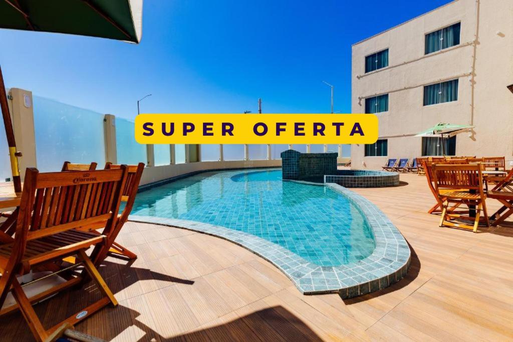 a swimming pool on a patio with chairs and a building at Átrios Beach Hotel in Natal