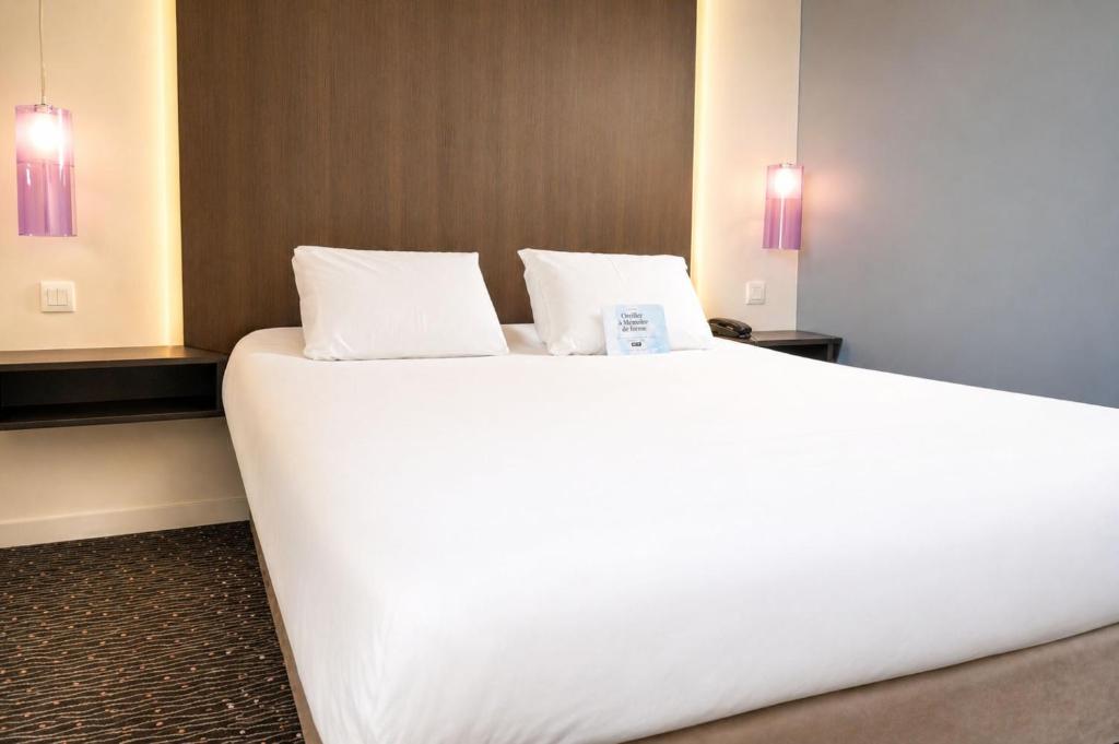 a large white bed in a hotel room at Kyriad Charleville Mezieres in Charleville-Mézières