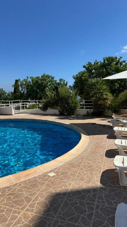 a swimming pool with chairs and an umbrella at Seaview Holiday Studio Peyia in Peyia