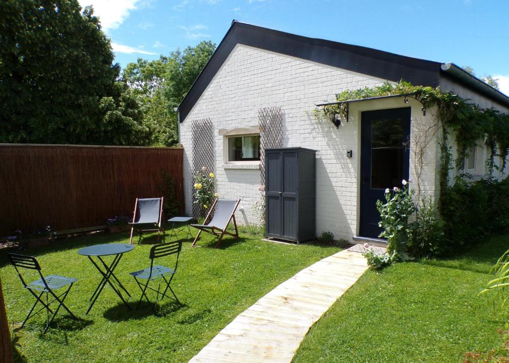a backyard with chairs and a table in the grass at Le Pavillon in Céroux-Mousty