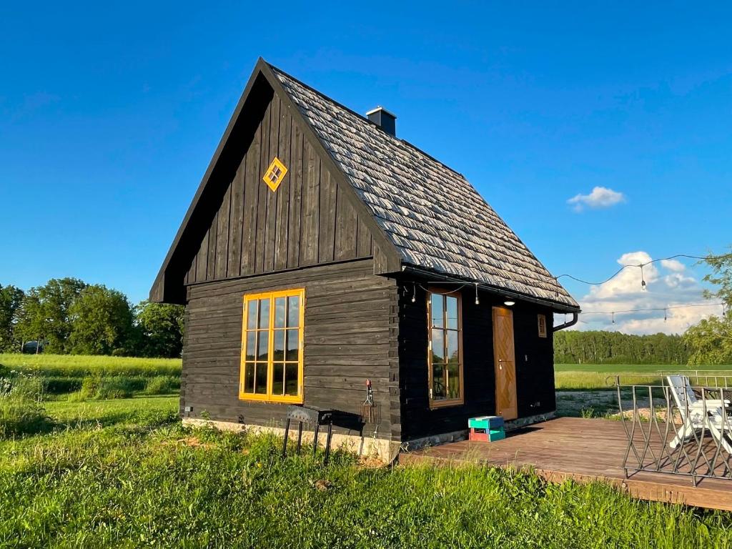 a small wooden building with a deck in a field at Sunset sauna Bauska in Jumprava