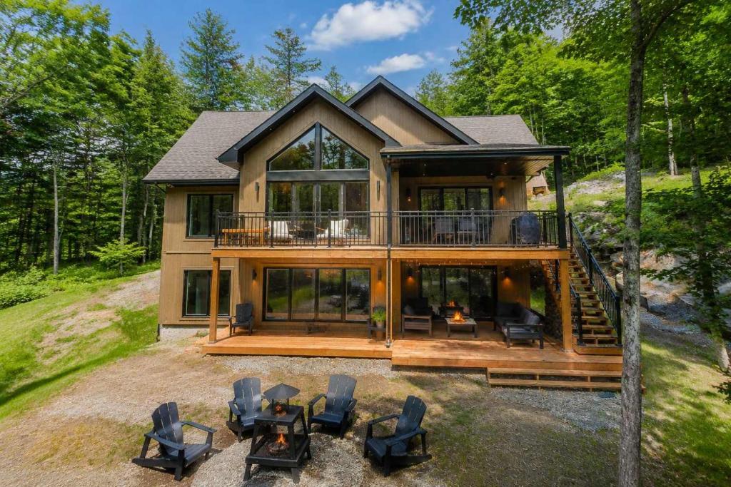 a large house with a large deck with chairs at Spa & Babyfoot - Chalet BOREA in Saint-Faustin