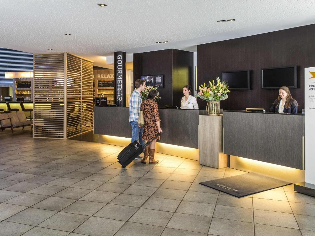 a man and woman waiting at a counter in a restaurant at Novotel Mechelen Centrum in Mechelen