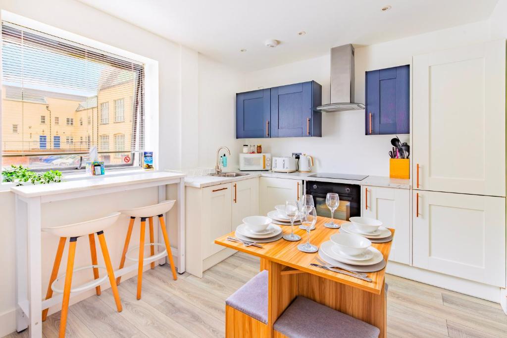 a kitchen with white cabinets and a wooden table at Modern City Centre Flat in Norwich