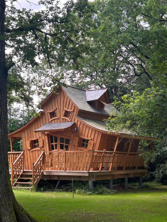a large wooden cabin with a large deck at Les Jardins de Valinor in Thénezay