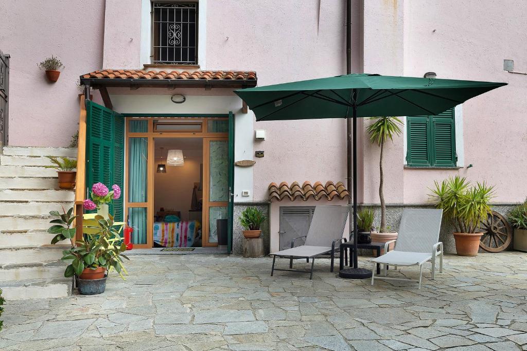 a patio with two chairs and a green umbrella at Quercia -in Caruggiu di Via Vecchia in Orco Feglino