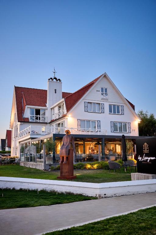 a large white building with a statue in front of it at Lebeaubylivingroom Hotel in Knokke-Heist