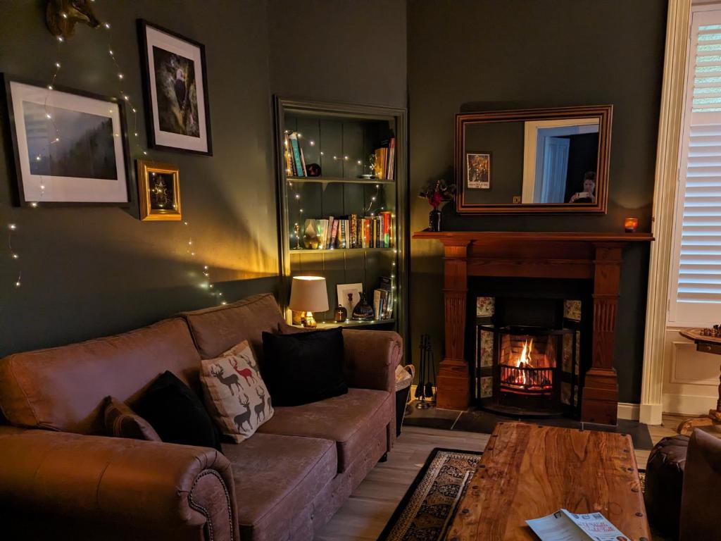 a living room with a couch and a fireplace at Mulberry Lodge -- a luxury cottage on the West Highland Way in Drymen
