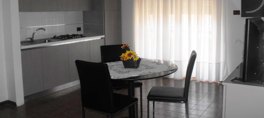 uma cozinha com uma mesa e cadeiras com um vaso de flores em Residence Royal em Siracusa