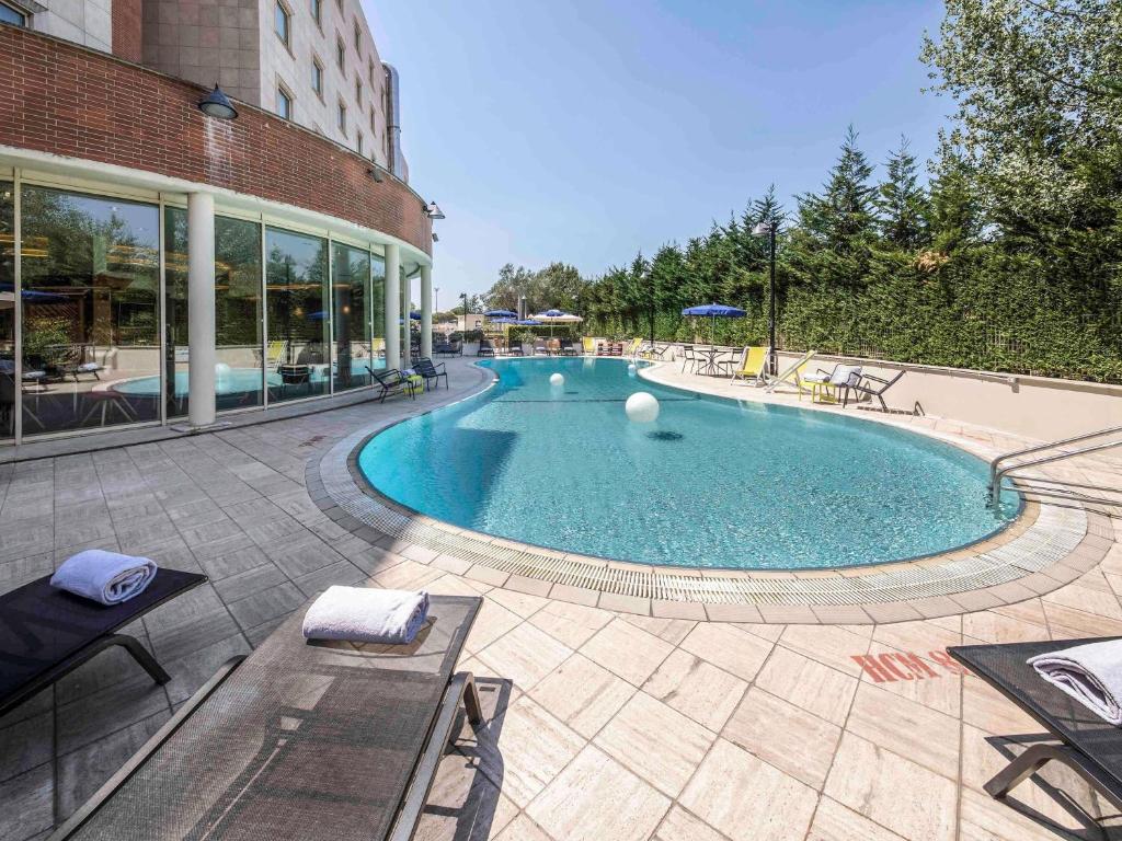 a large swimming pool in front of a building at Novotel Roma Est in Rome