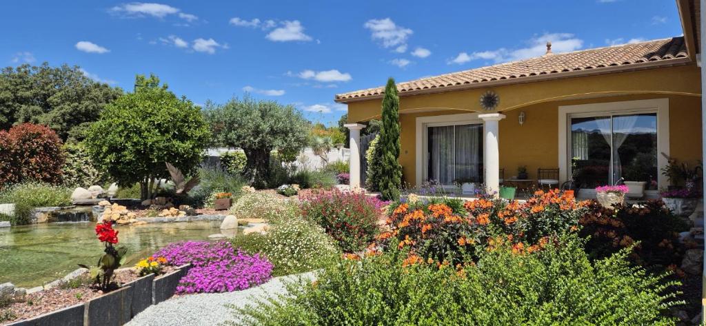 a garden in front of a house with flowers at Une Belle Histoire in Argelliers